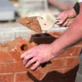 man laying a brick wall with mortar