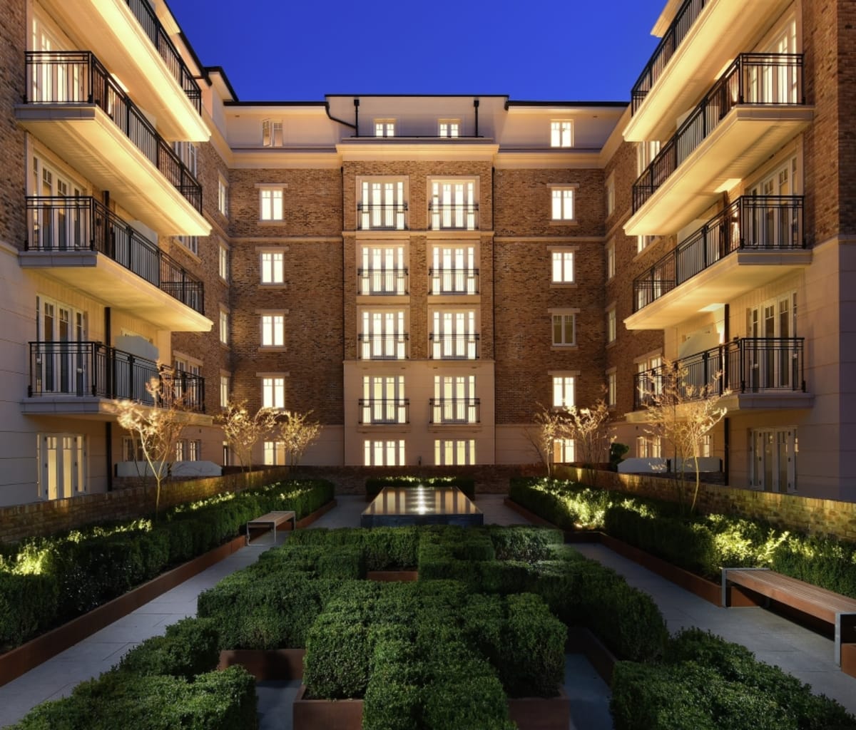 Nighttime view of cast stone detailed apartments overlooking a landscaped garden