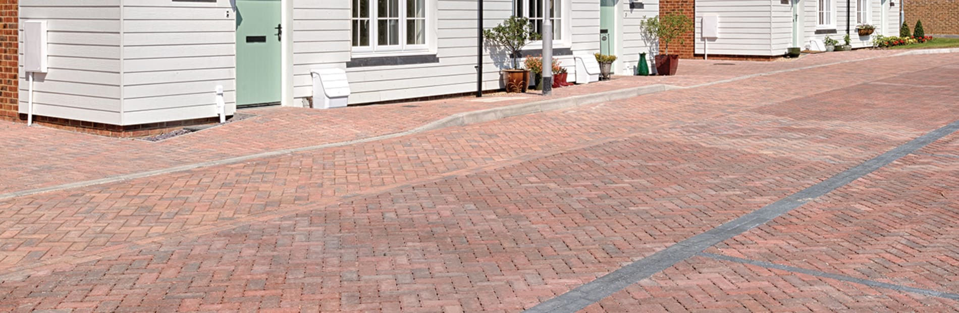 Red block paving in front of white house.