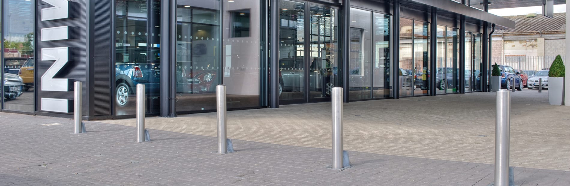 Silver bollards placed in front of a car dealership.