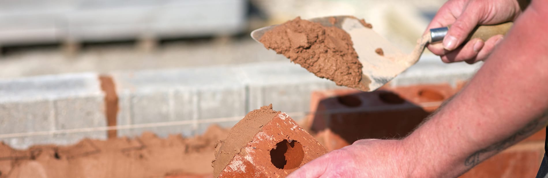 man laying a brick wall with mortar