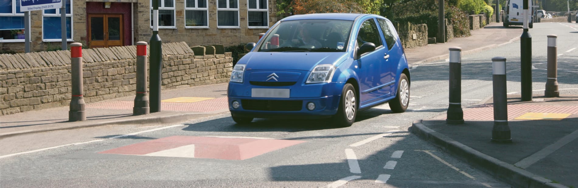 Car driving over red speed cushion at pedestrian crossing