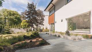 A grey patio with landscaped gardens either side
