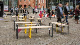 Members of the public sitting on and waling around temporary street furniture benches