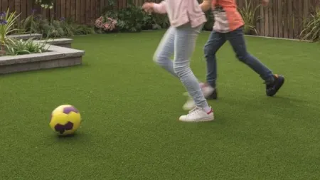 Two children playing football on artificial grass