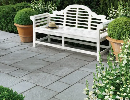 white bench on grey paving in a patio area