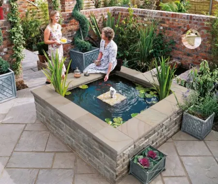 Two women in surrounding a water feature in a garden