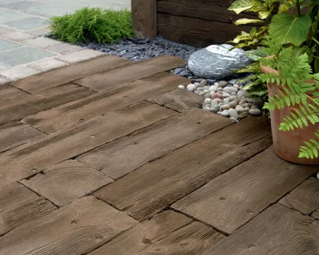 Dark brown Woodstone Sleepers laid in a garden area.