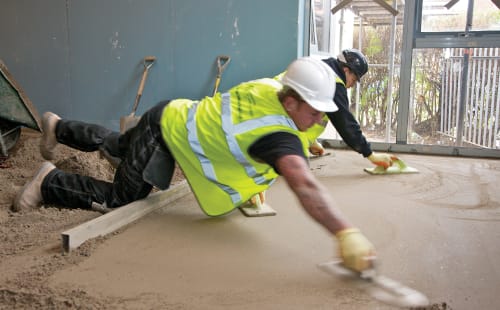 builder laying mortar on housing floor