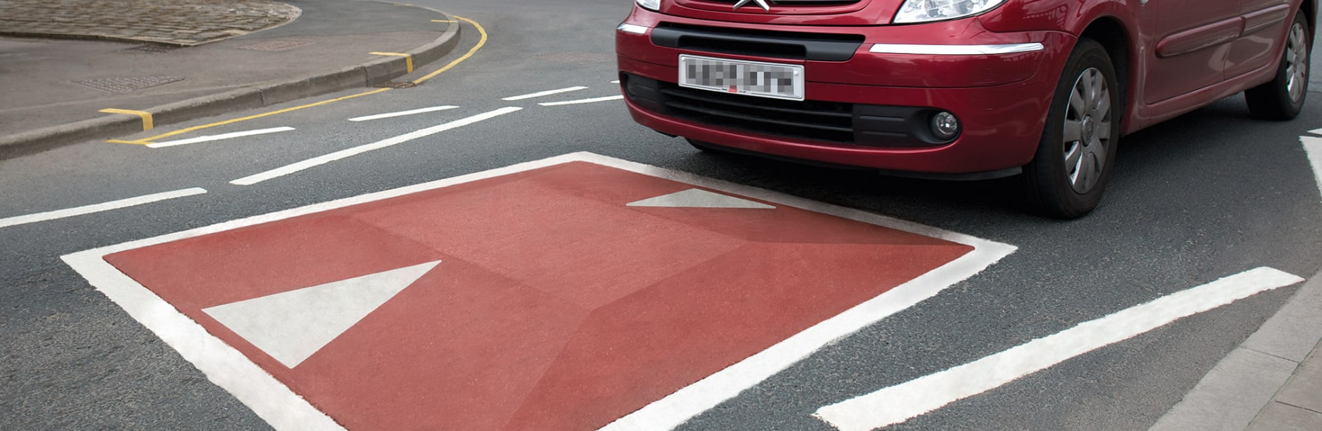 speed cushion in the road with a red car going over