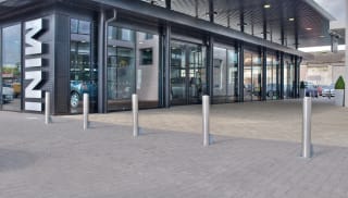 Silver bollards placed in front of a car dealership.