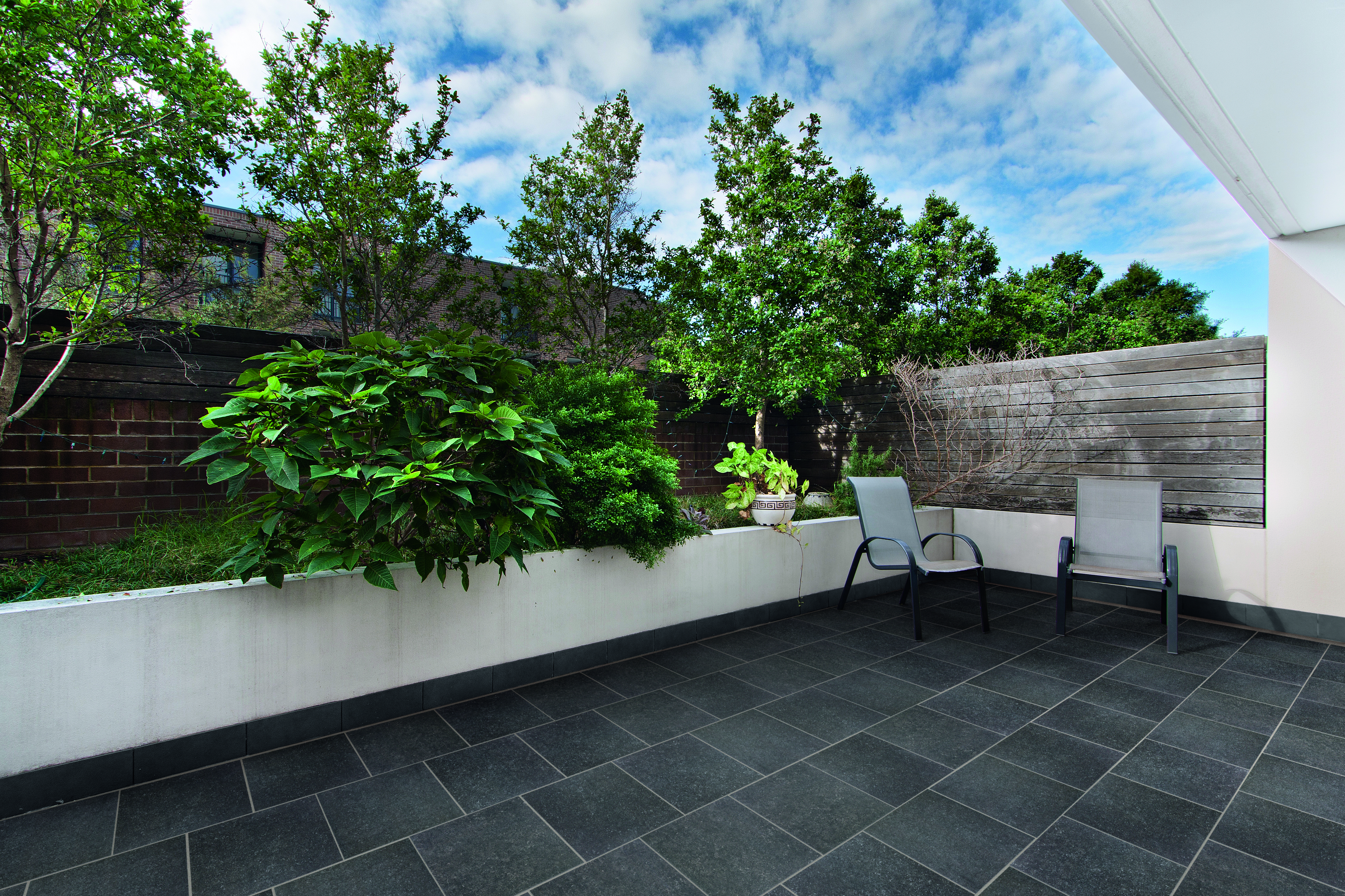 A black-tiled patio with two garden chairs