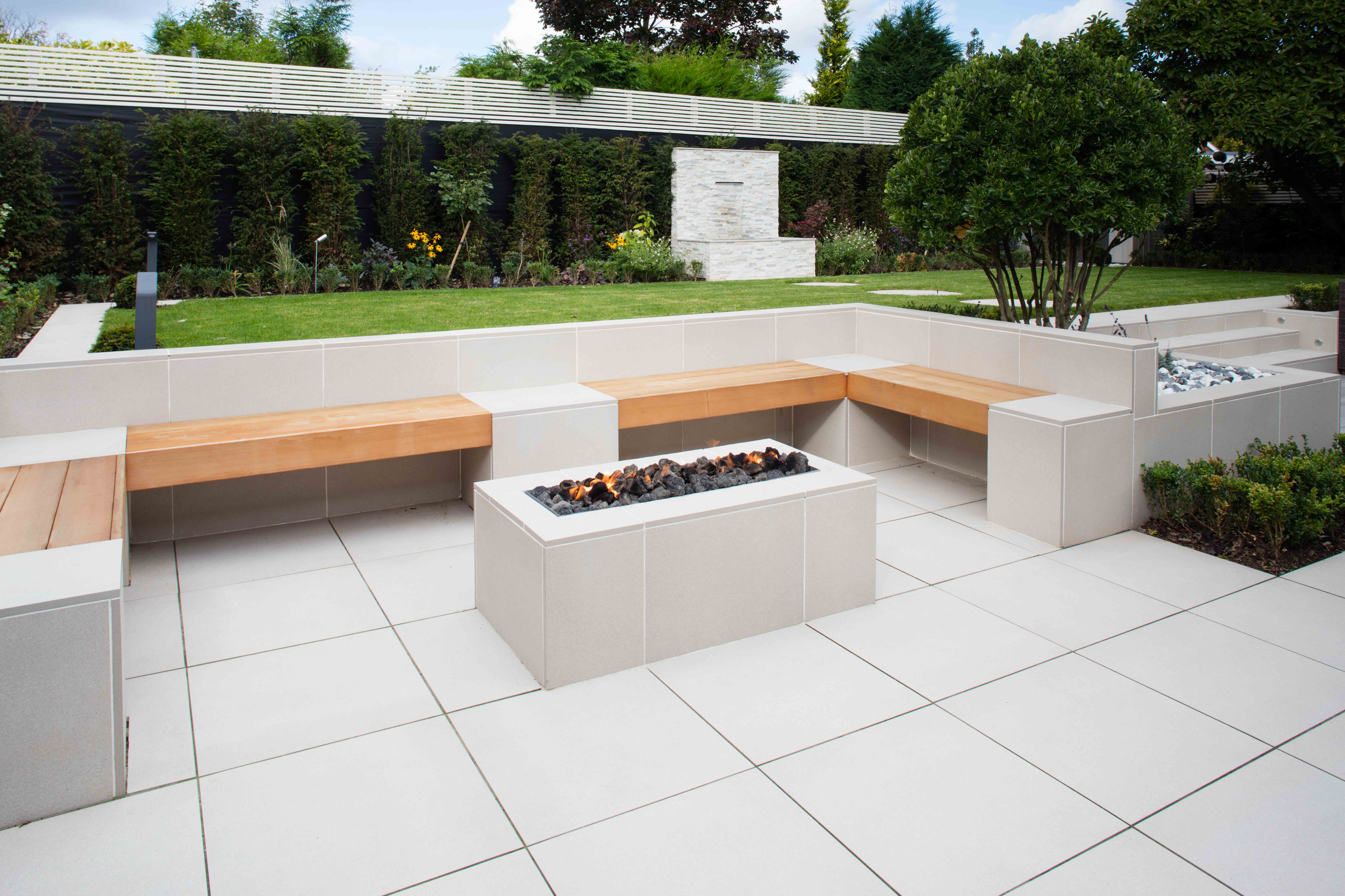 A firepit in the middle of a light-coloured garden paving area